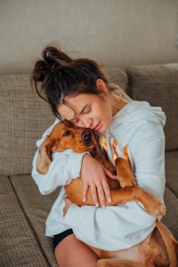 a young woman hugging her dog on a couch