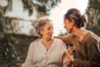 a woman is talking to an older woman in a park